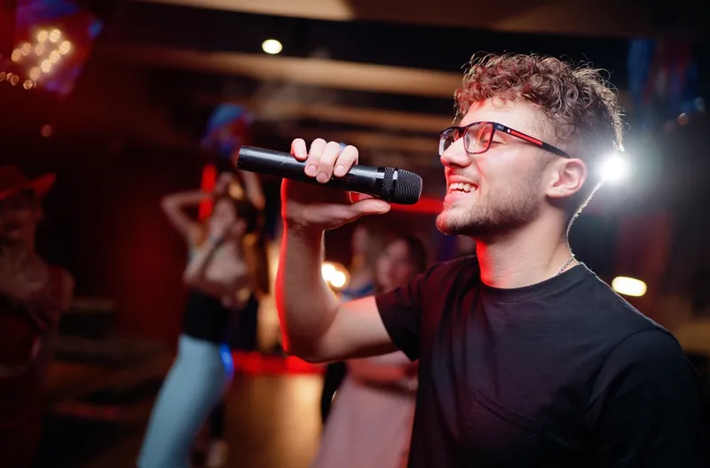 Junger Mann singt Karaoke auf einer Geburtstagsparty